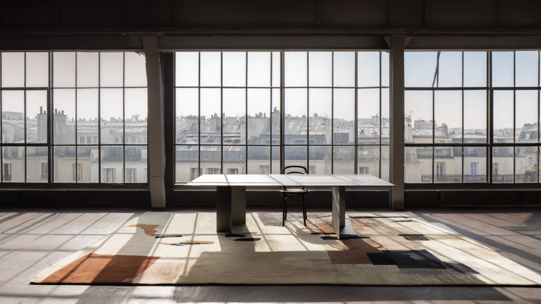 Tapis Benuta design abstrait dans un loft parisien lumineux avec grandes baies vitrées et vue sur les toits de Paris